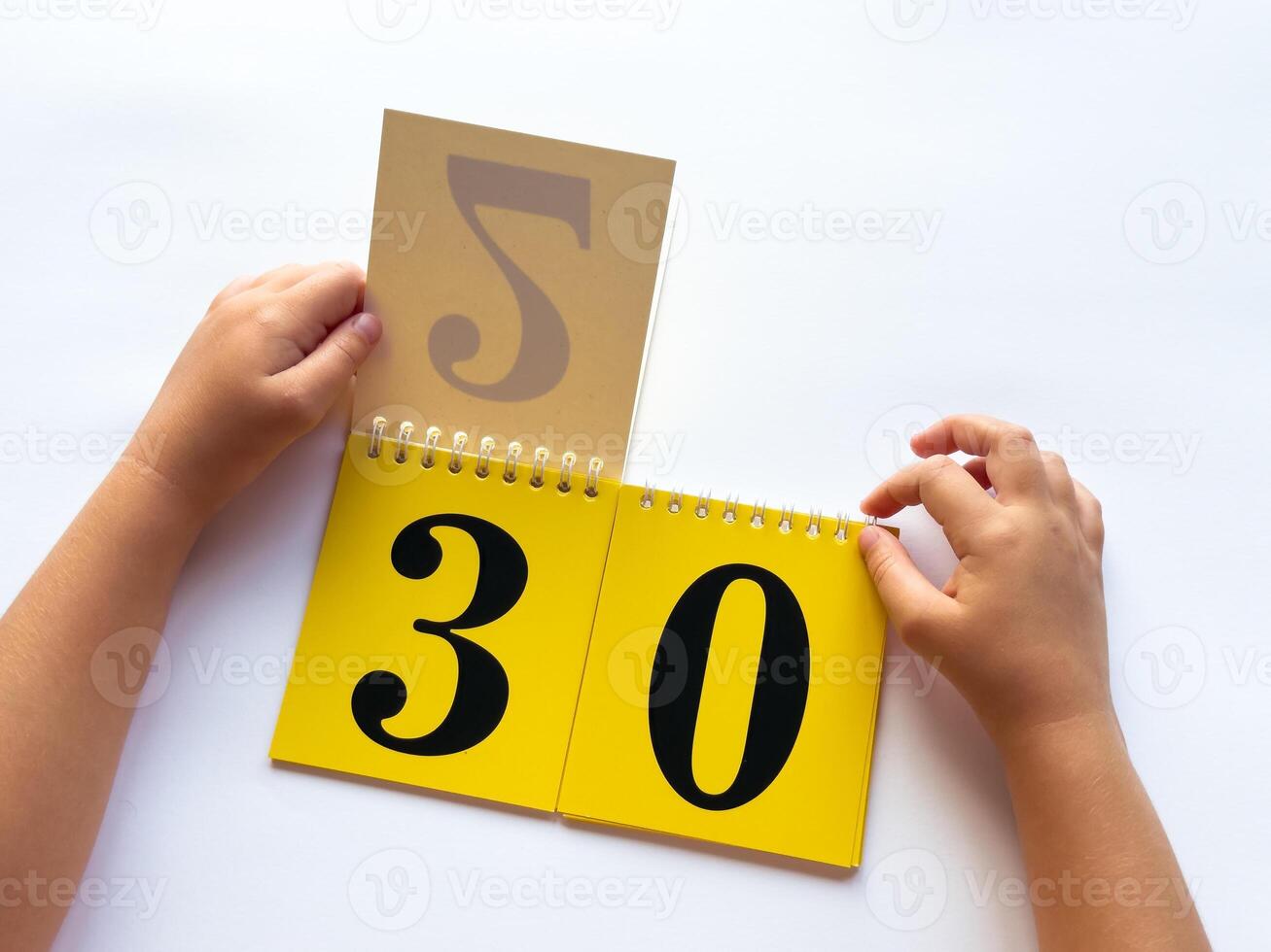 Childs hands flip through yellow pages with numbers on a white background photo