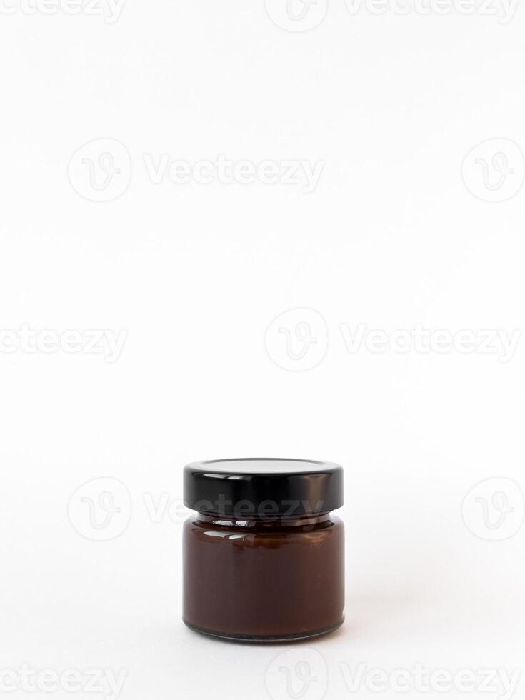 Minimalist display of small brown glass jar with black lid on white background photo