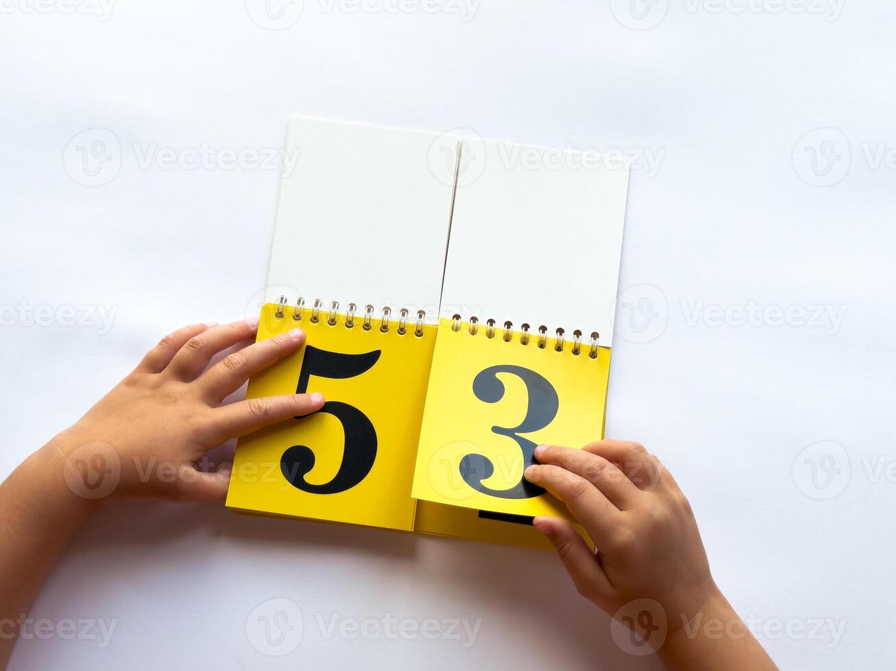Child flipping yellow calendar pages with numbers on white background photo