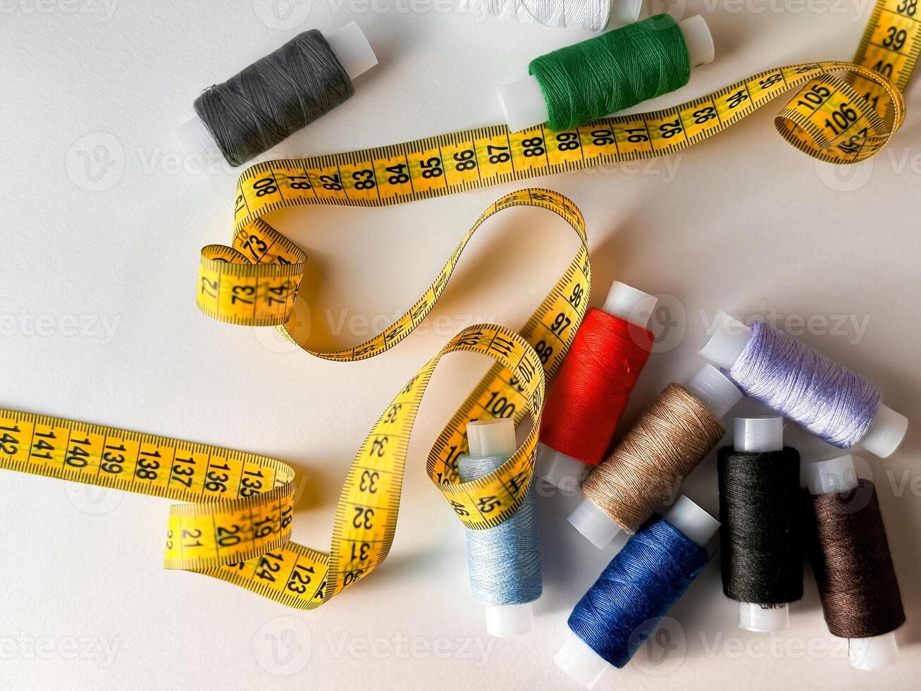 Colorful spools of thread and yellow measuring tape for sewing crafts photo