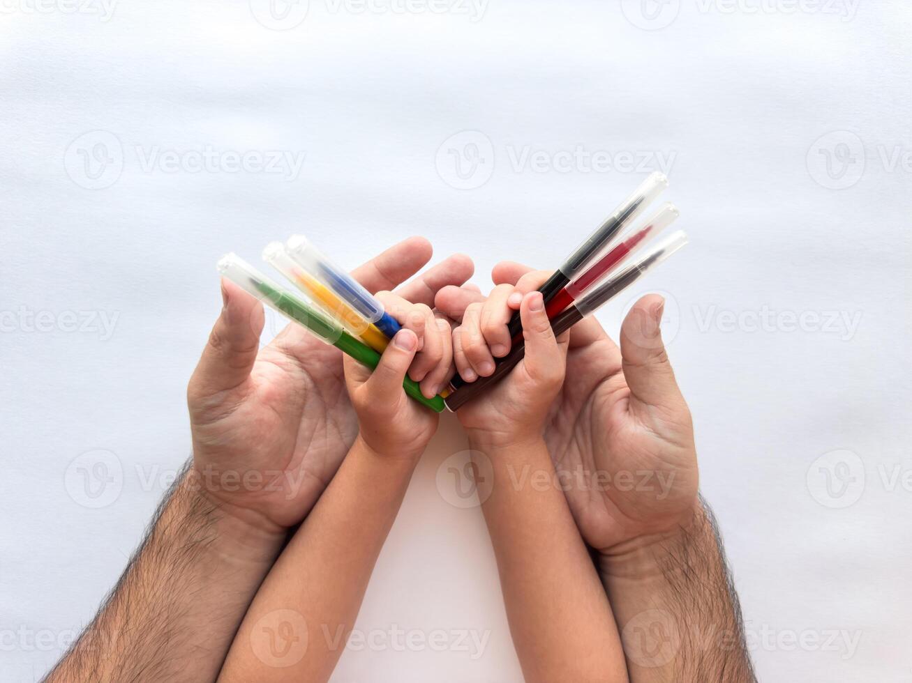 Family bond. Adult and child hands holding colorful paint tubes together photo