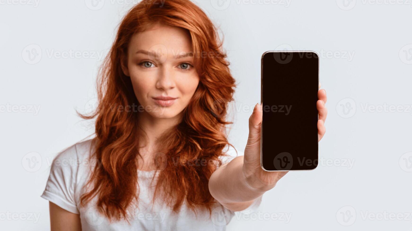 Teen Girl Showing Mobile Phone Empty Screen Advertising App Posing Over White Studio Background. Mockup, Panorama photo
