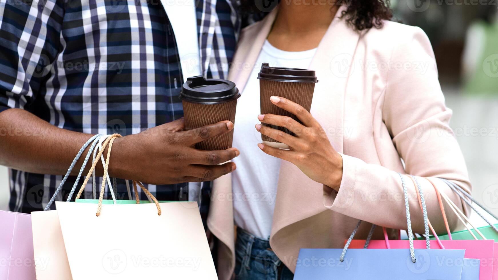 Unrecognizable Black Couple Resting With Coffee After Successful Shopping In Mall, Shopaholic Spouses Carrying Lots Of Bright Paper Shopper Bags, Enjoying Seasonal Sale Offers, Cropped Image photo
