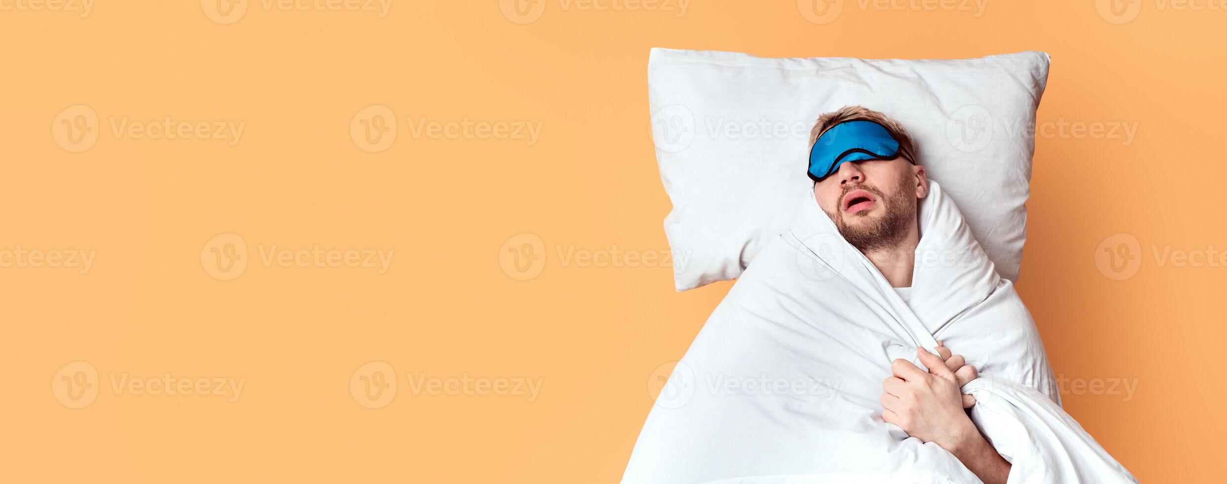 Sweet sleep in comfortable bed. Guy sleeps in mask, top view, free space photo