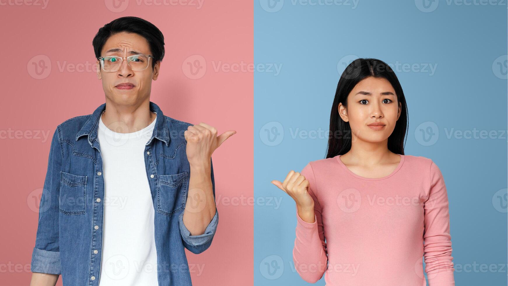Asian couple pointing at each other with facial expression of disgust, grey studio background photo