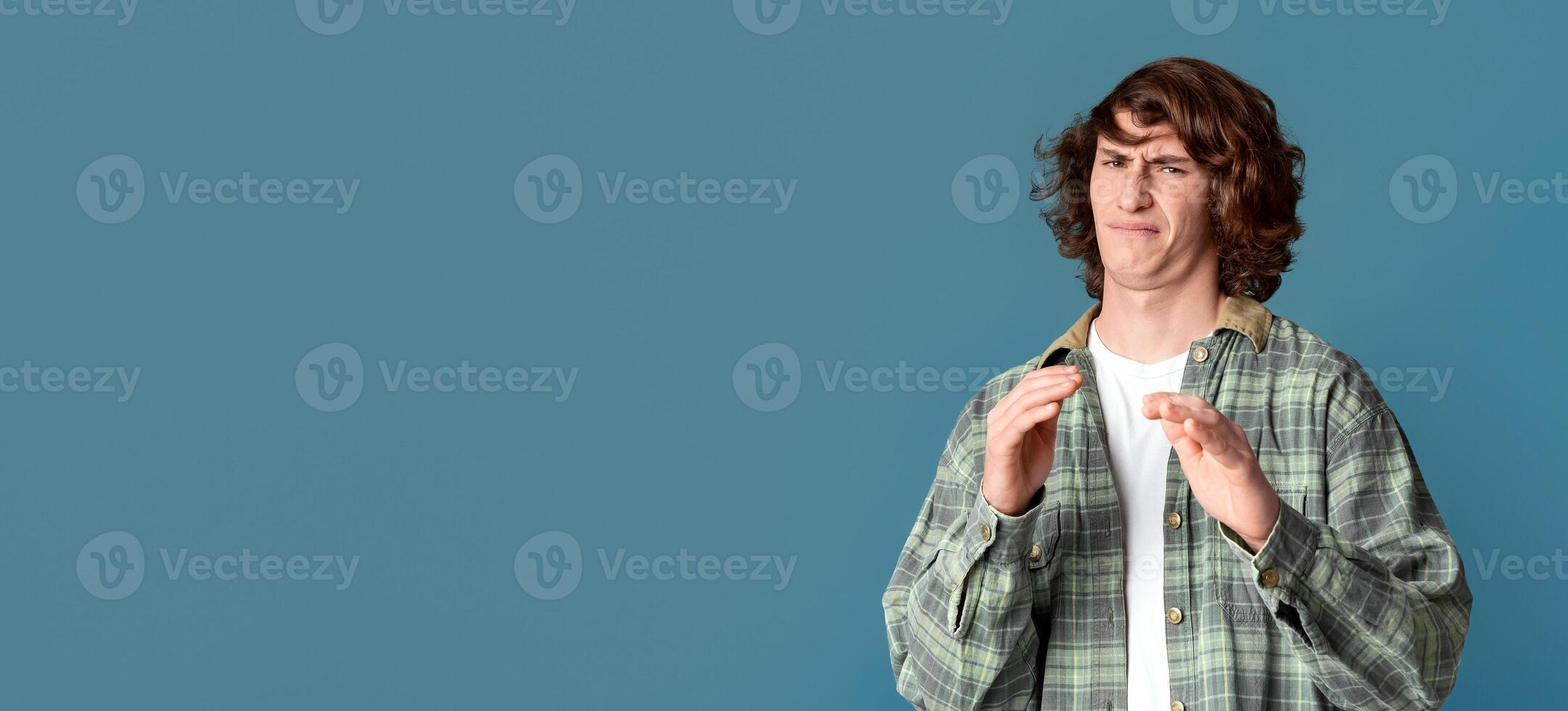 Expressing disgust. Millennial guy with curly hair feeling repulsed on turquoise background photo
