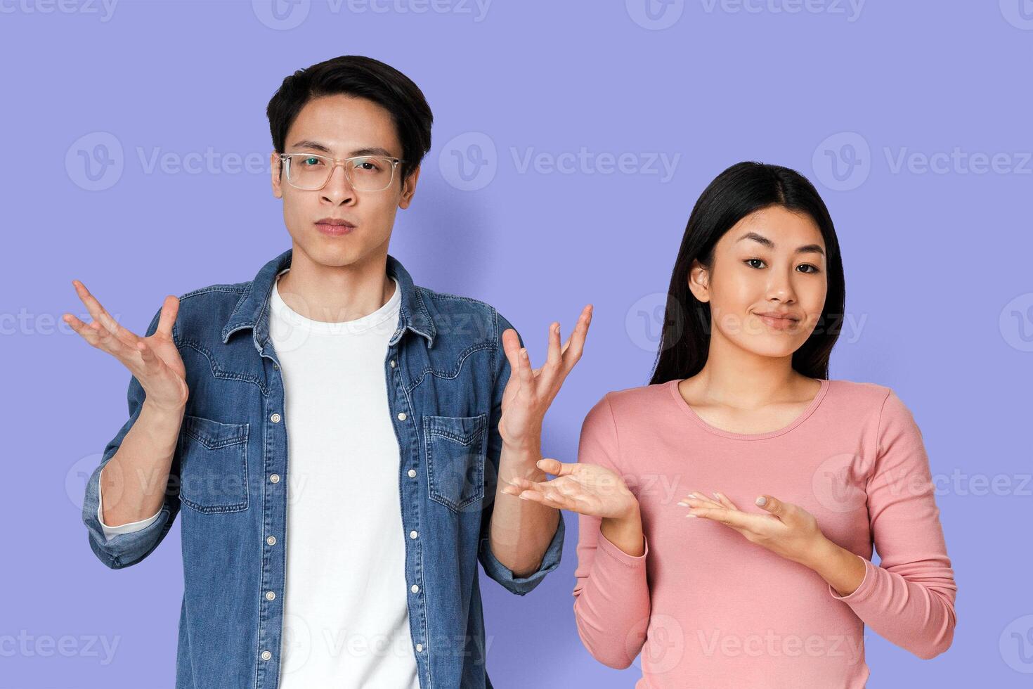 Sarcastic asian girl pointing at her emotional boyfriend, fighting during isolation over grey background photo