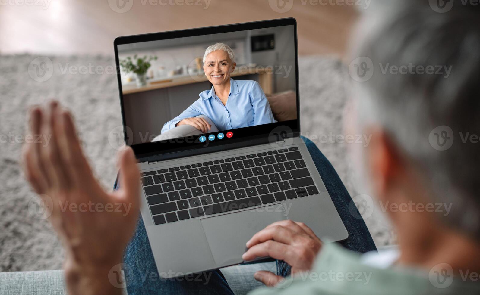 An elderly woman shares a warm smile while engaging in a call. Her cozy home setting and joyful demeanor create a heartwarming connection with her loved one. photo