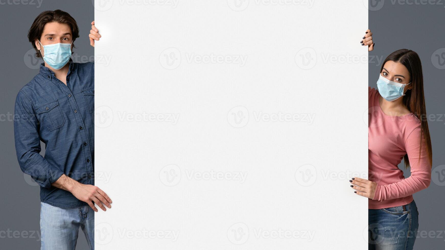Millennial Couple In Protective Masks Holding Big White Advertisement Board With Free Place For Your Text, Standing Over Light Background, Panorama photo