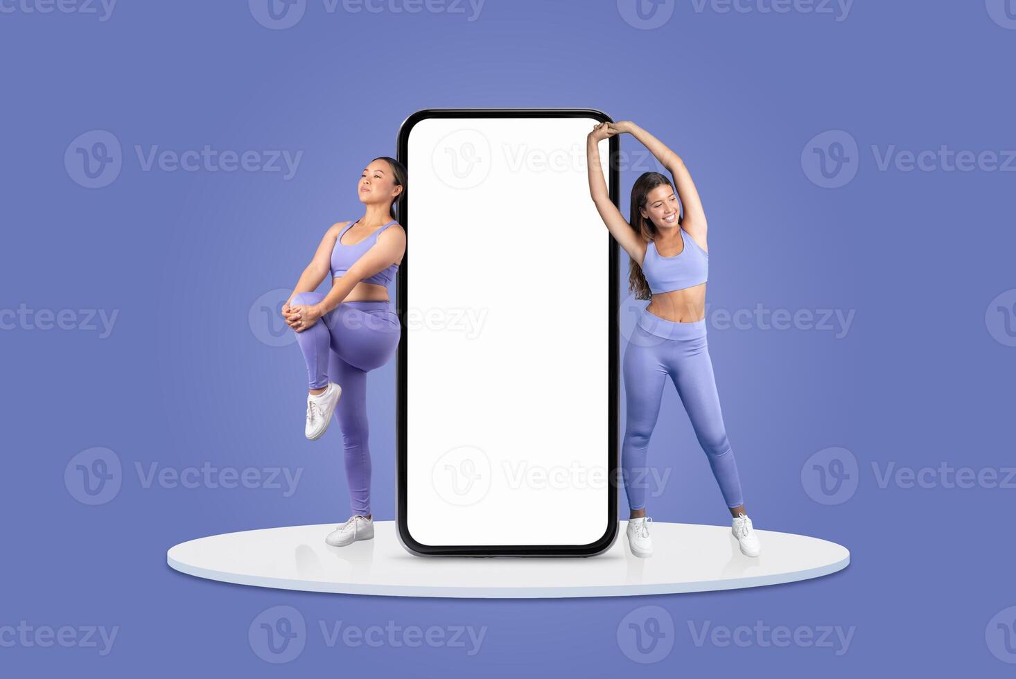 Two women in athletic clothing are engaging in stretching exercises next to a large, blank smartphone. The backdrop is a calming blue, creating a vibrant setting for their activity. photo