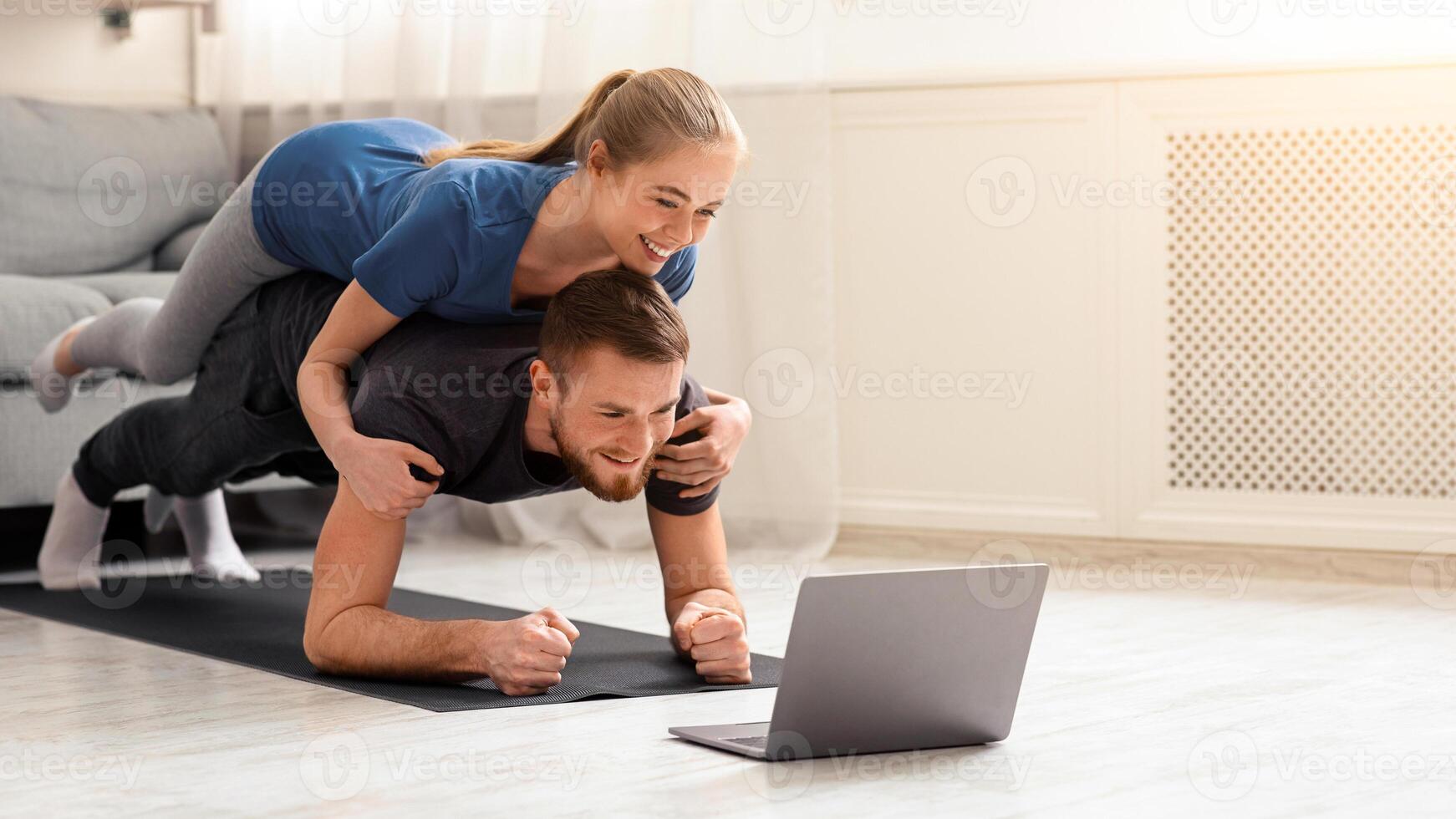 Online workout. Young man and woman practicing plank exercise with online tutorial at home, free space photo