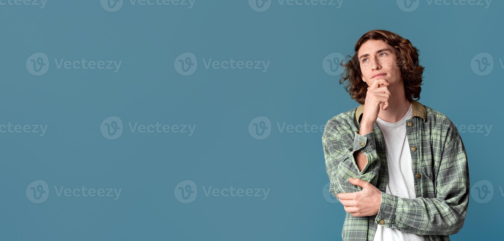 Dreamy handsome guy thinking on turquoise background, blank space. Panorama photo