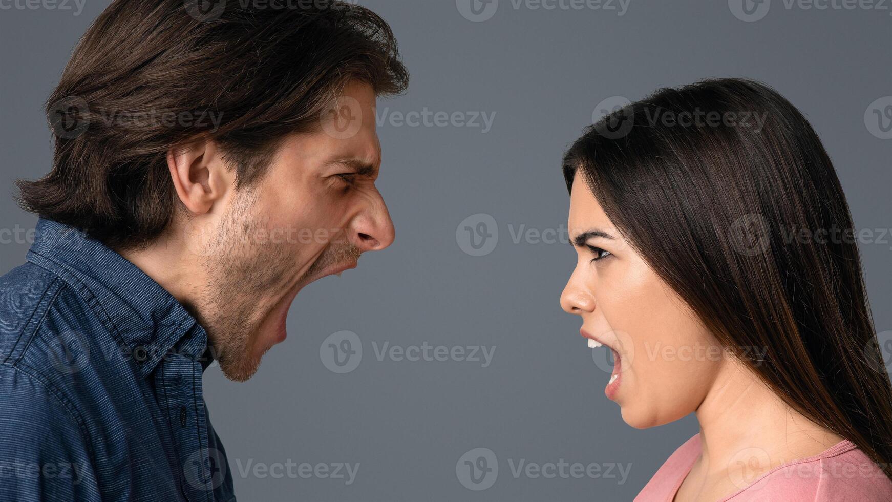 Relationship Crisis. Angry Young Couple Screaming At Each Other Over Light Studio Background, Side View photo
