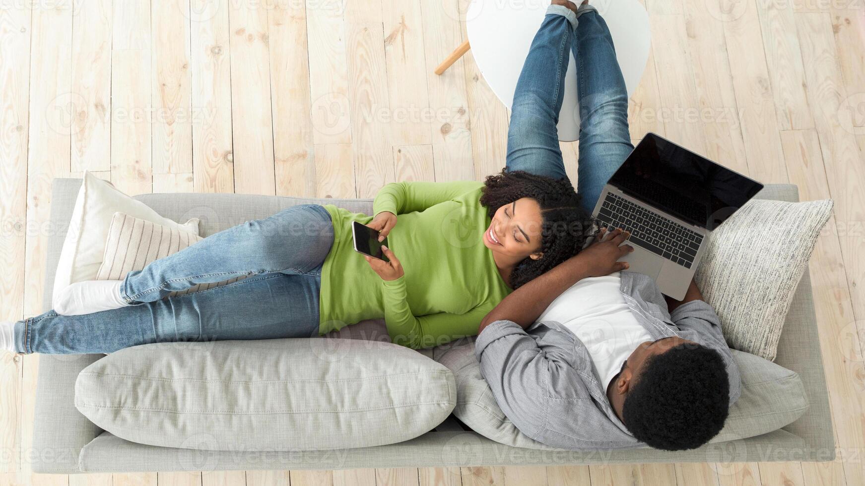 Top View Of Happy Black Couple Spending Time At Home. Man Using Laptop And Woman Surfing Internet On Smartphone, Copy Space photo