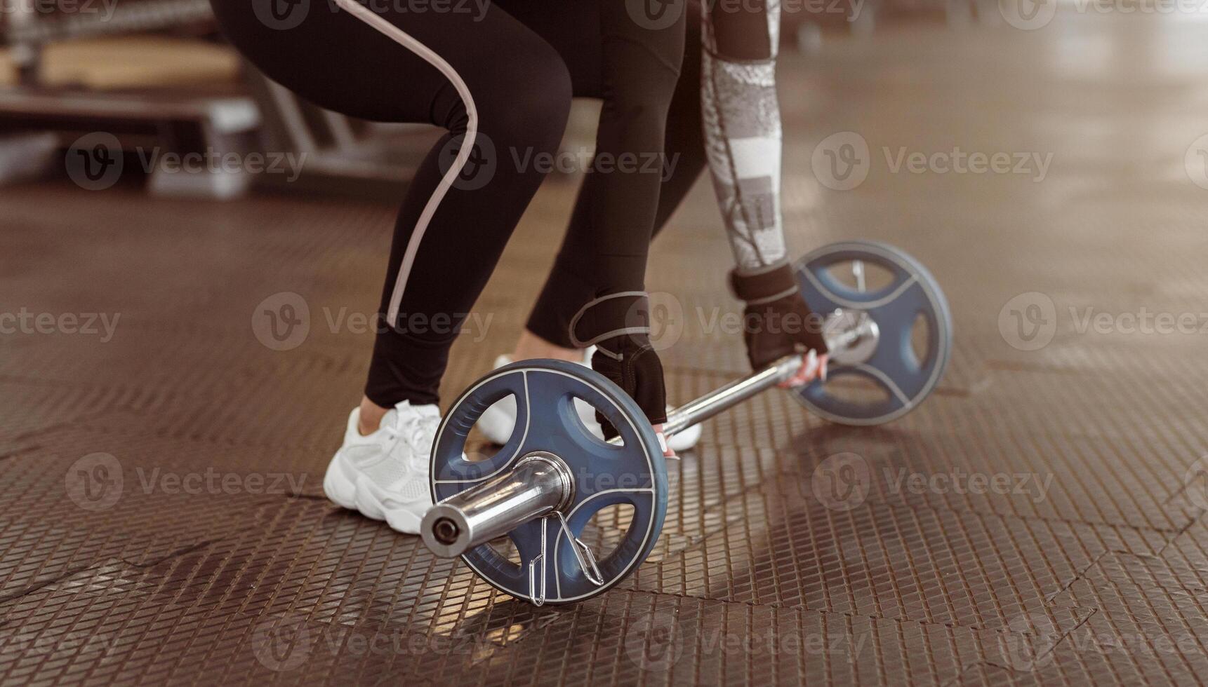 Sporty lady with barbell exercising in gym, closeup photo