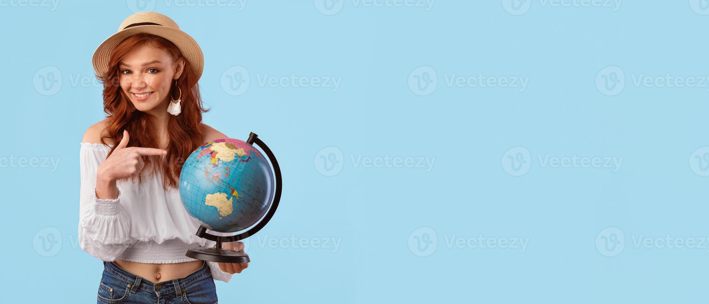 Travel The World. Smiling Girl Holding Earth Globe Pointing Finger Posing In Studio Over Pink Background. Panorama, Empty Space photo