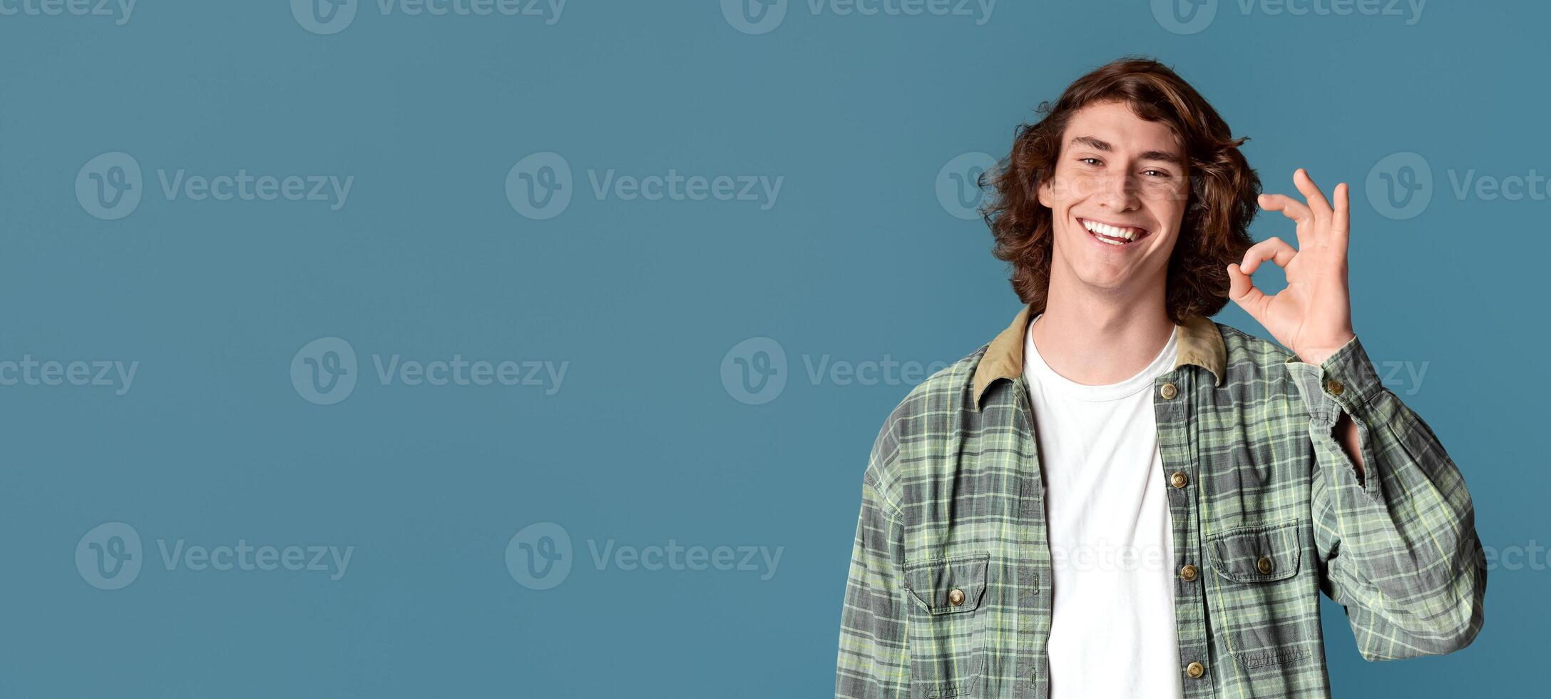 Agreement gesture. Happy Caucasian guy showing OK gesture on turquoise background photo