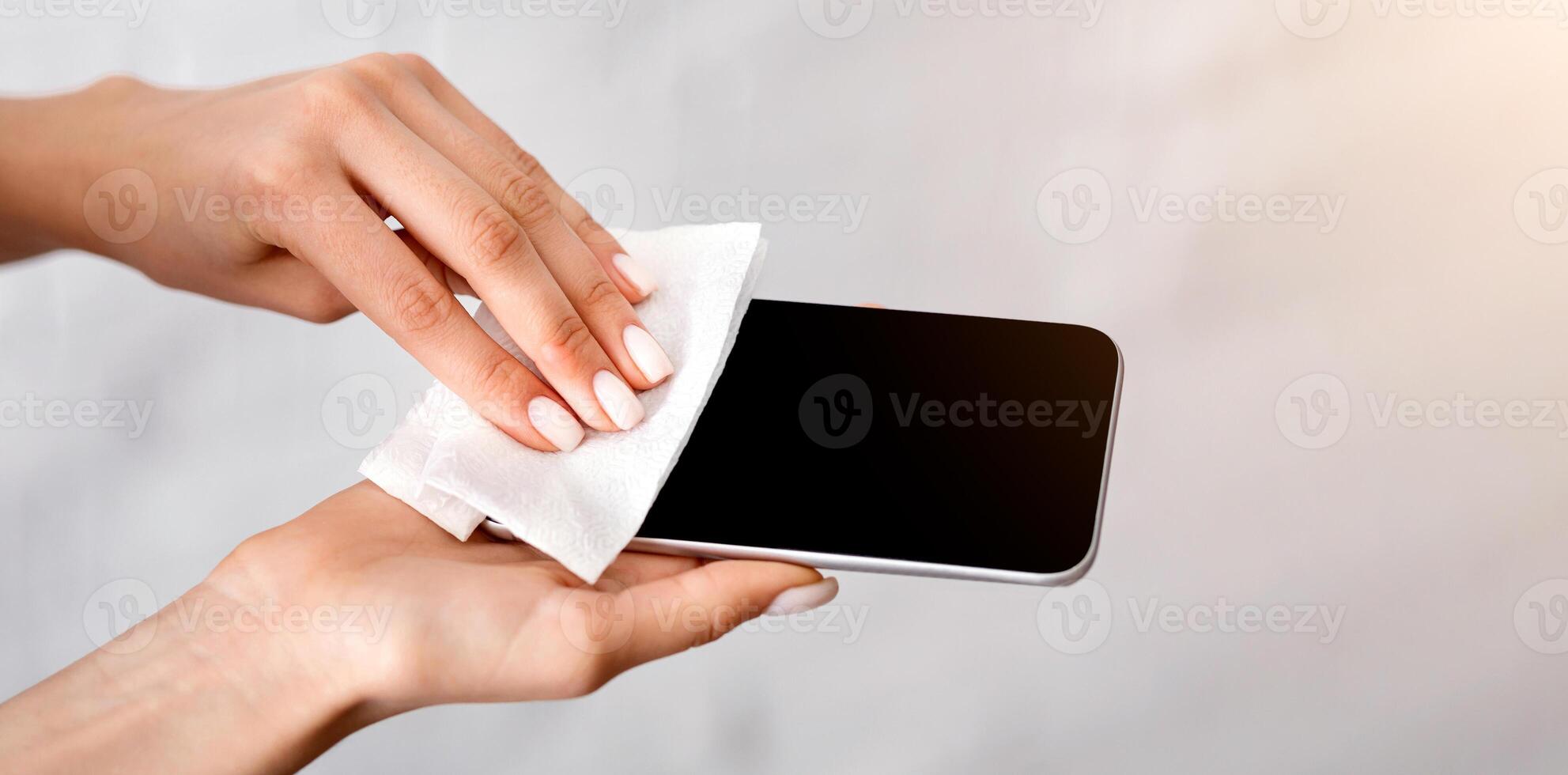Coronavirus epidemic concept. Girl rubs smartphone antiseptic wipe photo