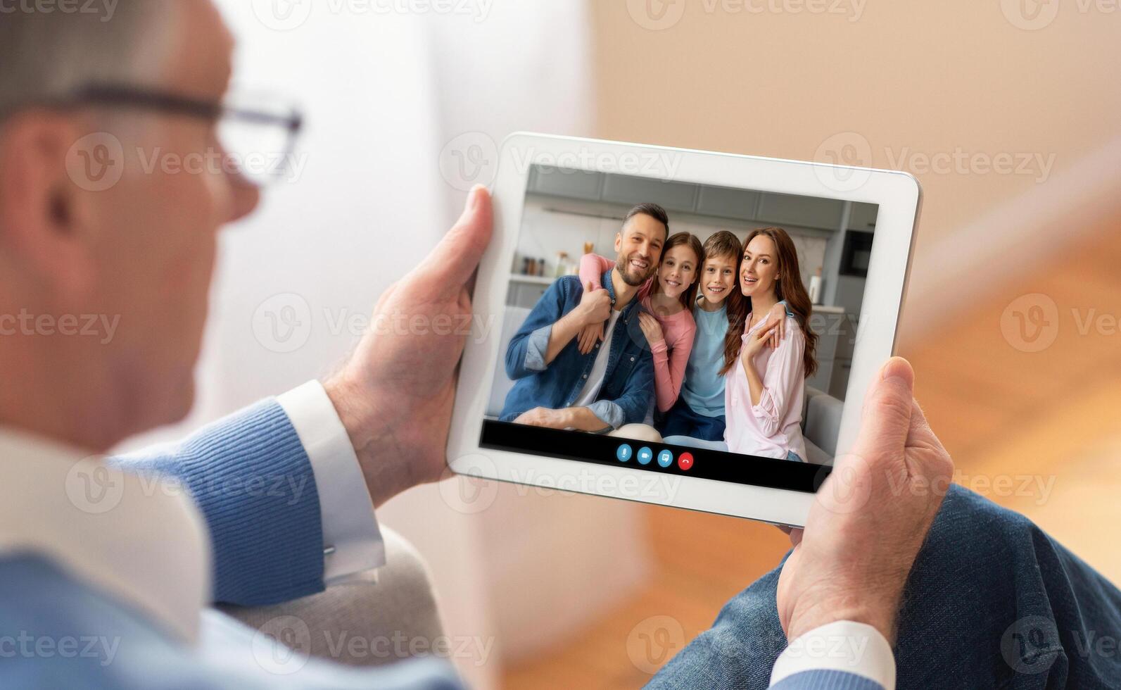 A man enjoys a call with his family, smiling as they connect on a tablet. The warm setting creates a cozy atmosphere filled with love and togetherness. photo