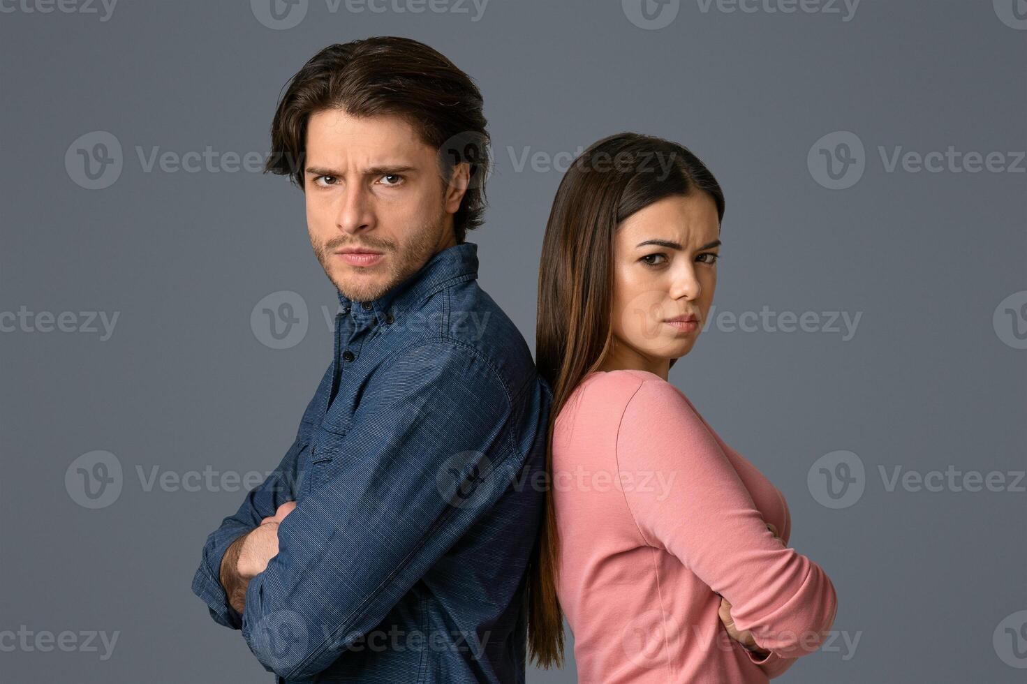 Relationship Crisis. Offended young couple standing back to back with folded arms and looking at camera, light studio background with copy space photo