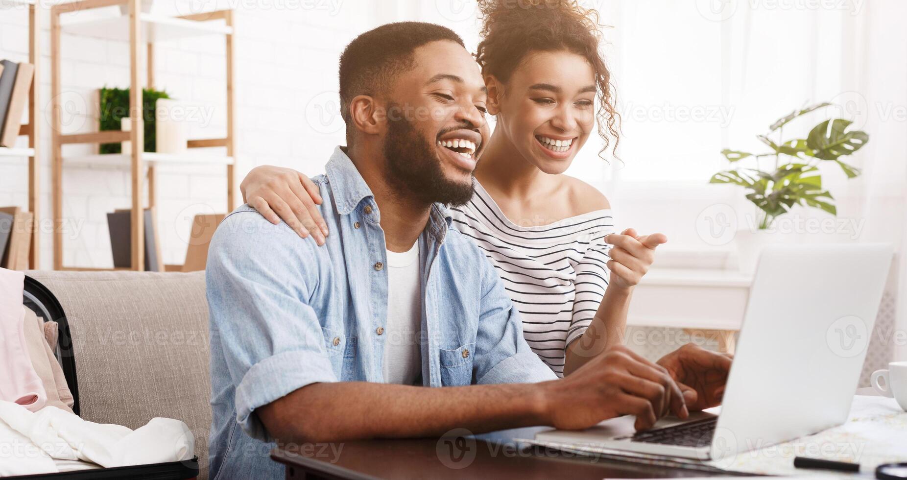 African-american couple searching tour online on laptop, preparing for holidays photo