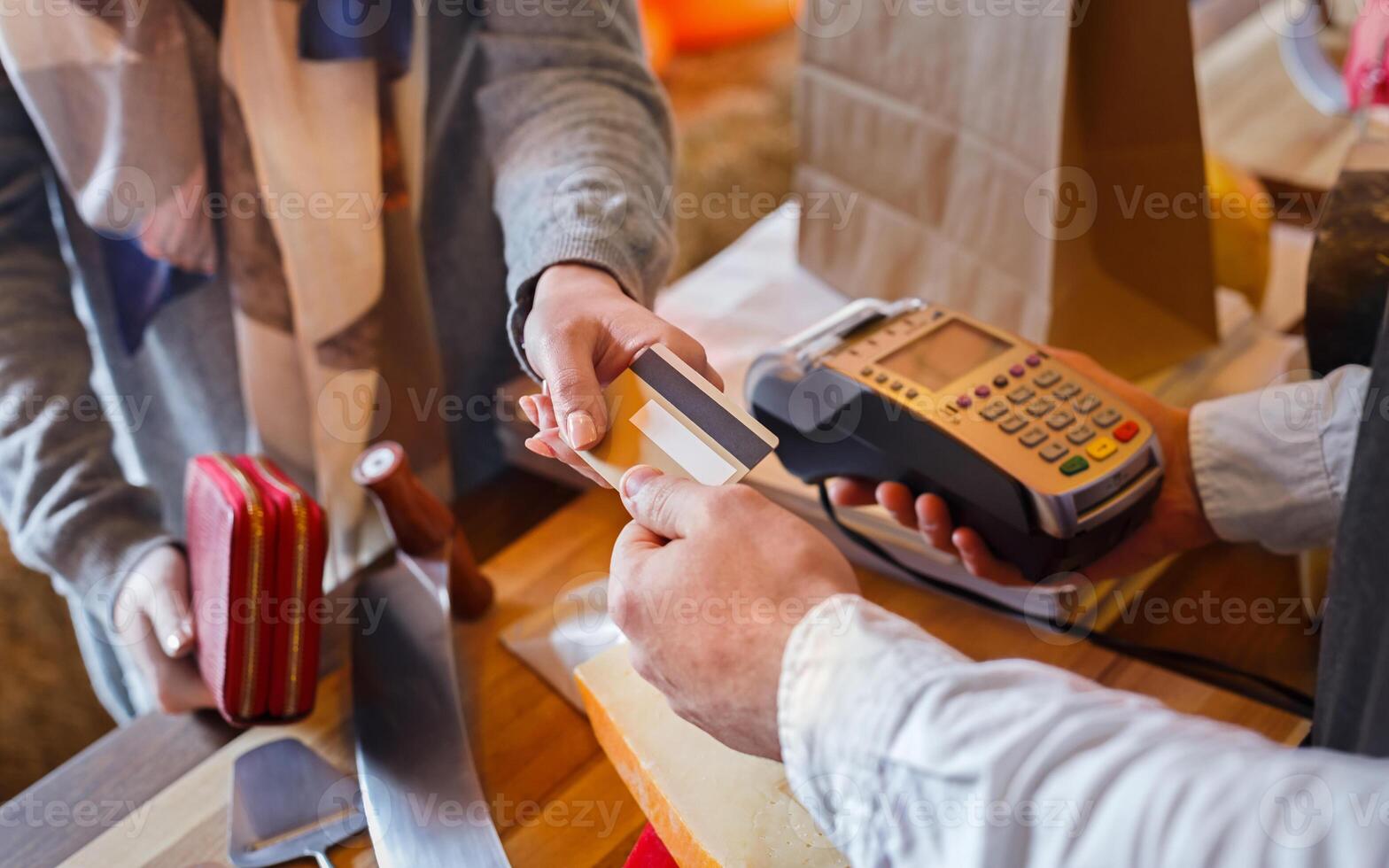 Credit card payment service. Customer paying for order of cheese in grocery shop. photo