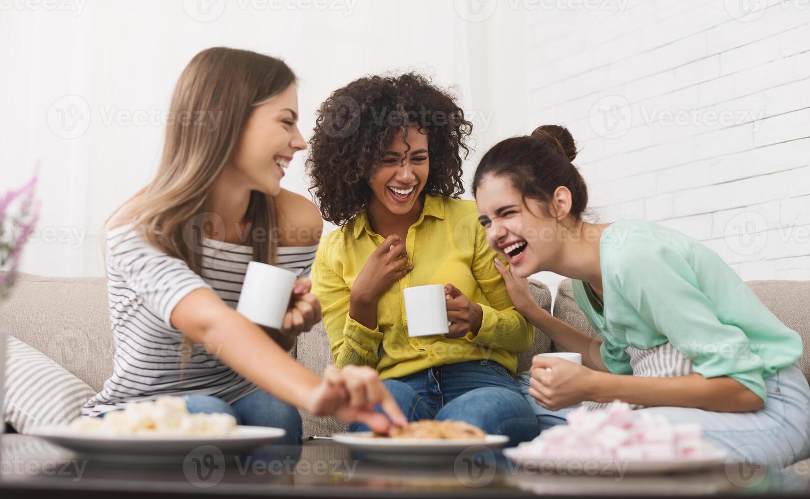 Best friends drinking tea, eating cookies and talking at home photo