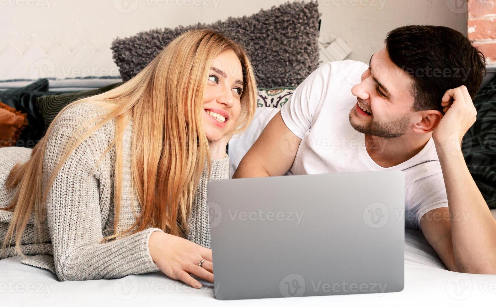 Movie time. Young family with laptop resting on sofa at home photo