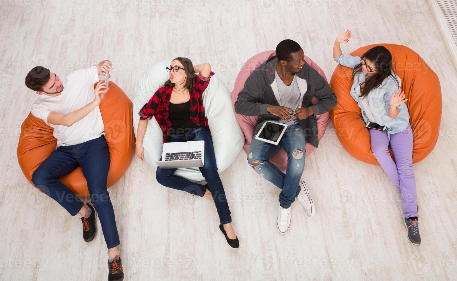 Multiethnic young friends, students have fun in home interior, using gadgets photo