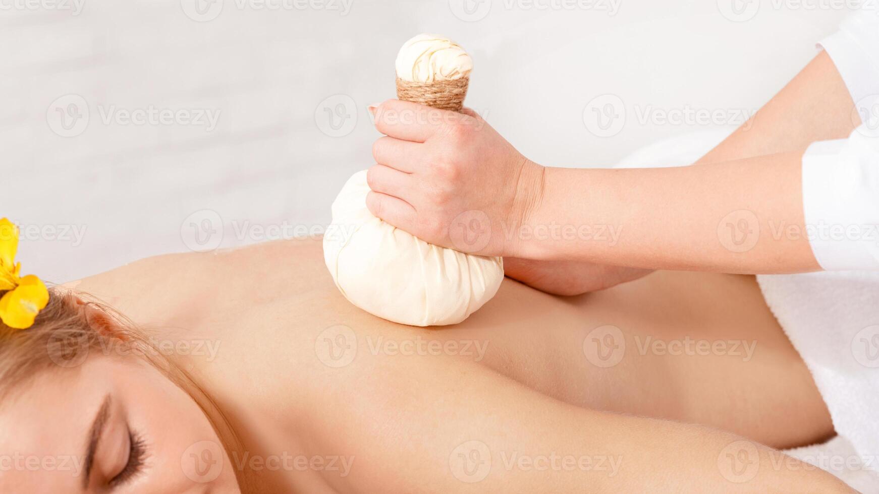 Ayurvedic procedure. Professional doing massage with herbal bags for girl, free space, cropped photo
