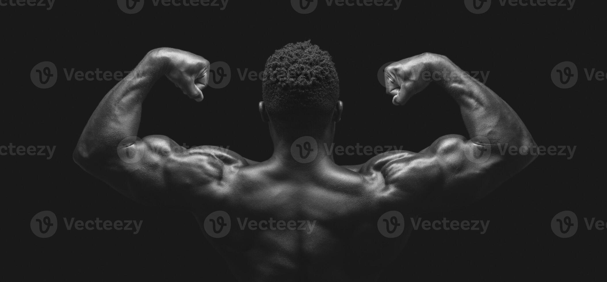Double biceps pose in black and white. African athlete showing his arms, back view photo