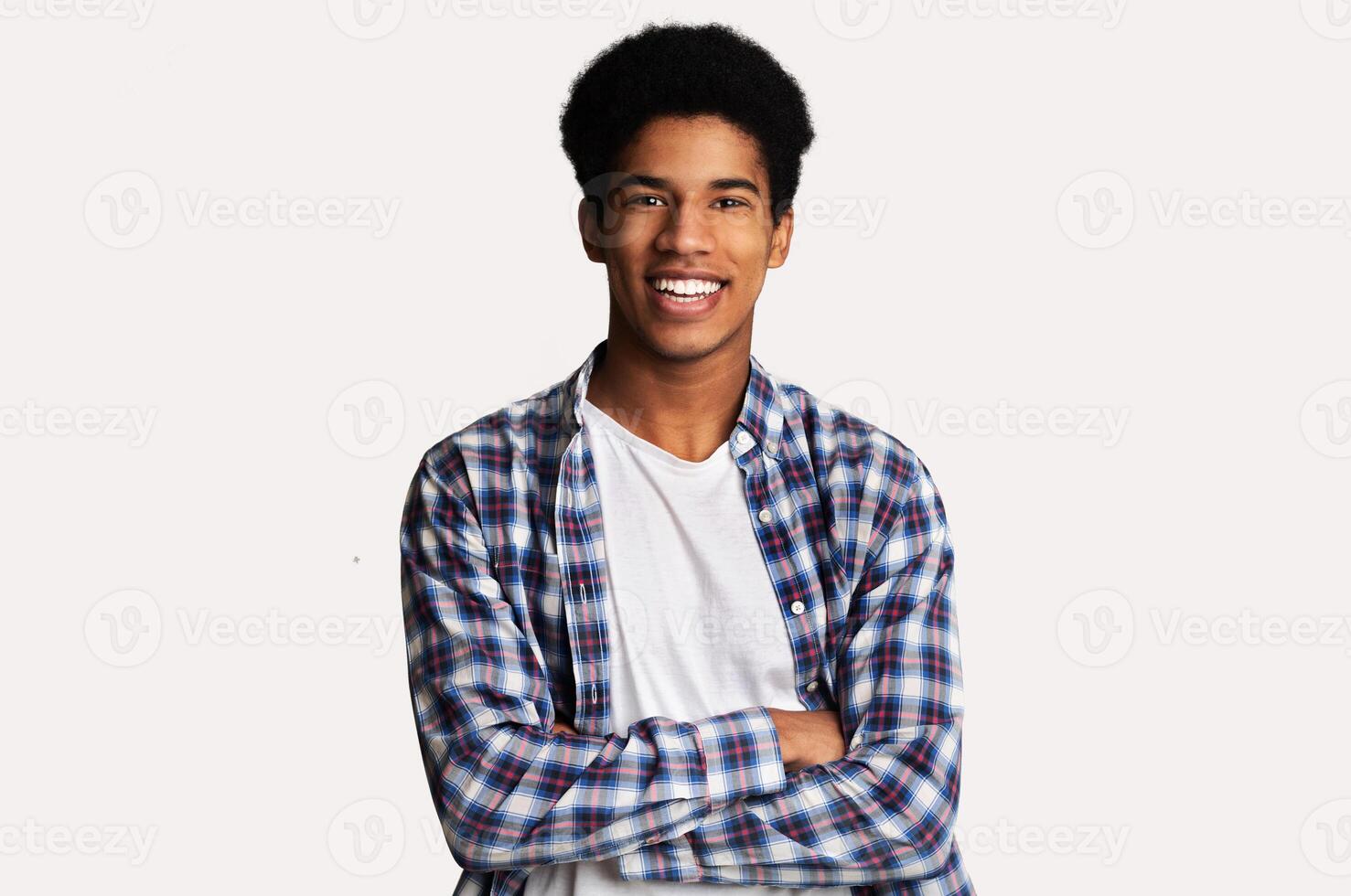 Happy teen guy posing with crossed hands and smiling to camera over white background photo