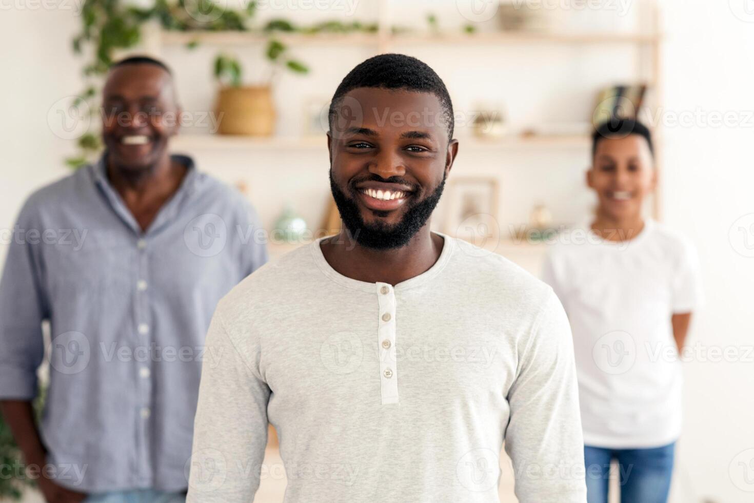 Three Generations. Smiling Black Father, Son And Grandfather Posing Standing At Home, Looking At Camera, Selective Focus On Millennial Man photo