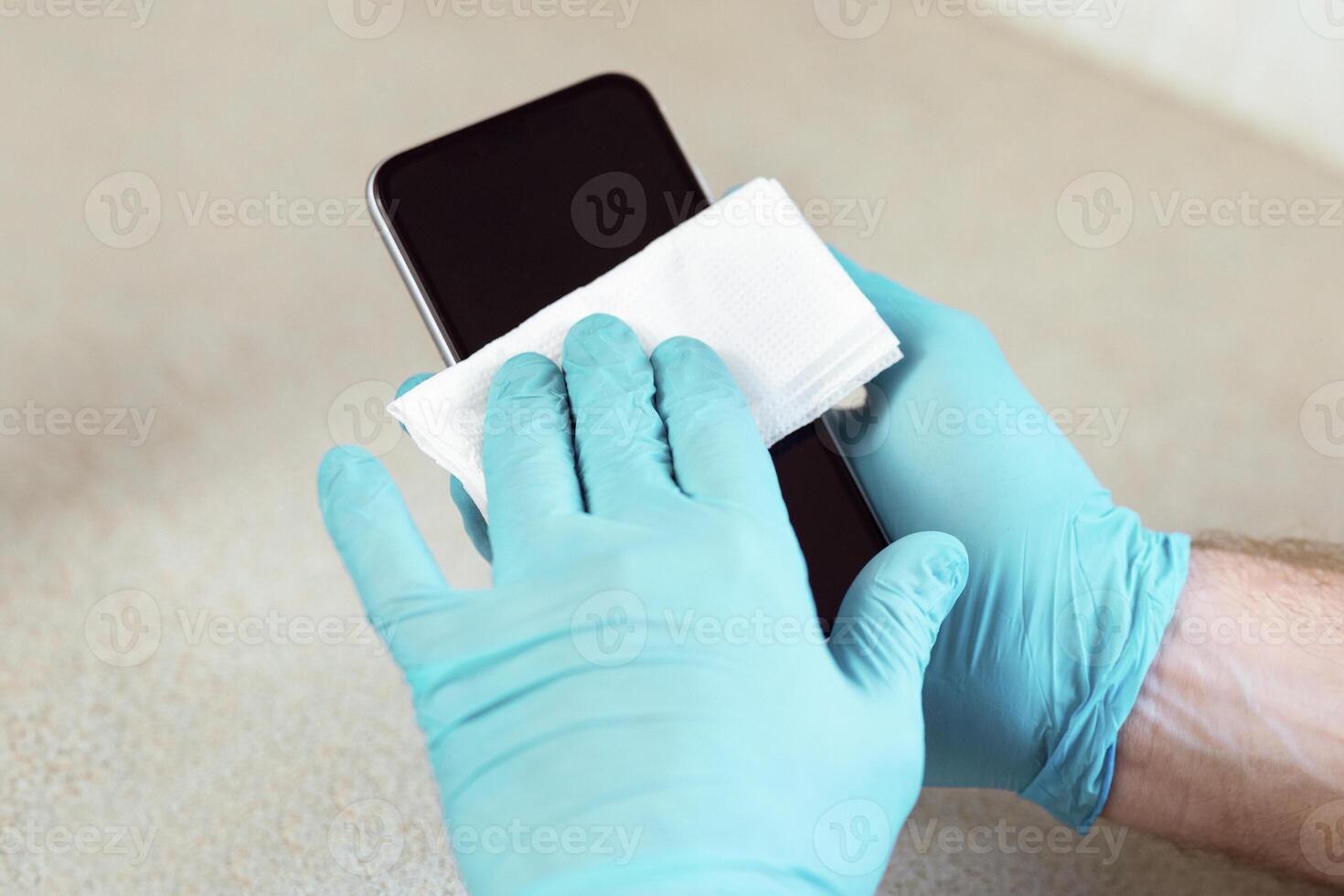 Man Sterilizing Mobile Phone Before Use At Home. Gadget Hygiene During Coronavirus Pandemic. Panorama, Cropped, Selective Focus photo
