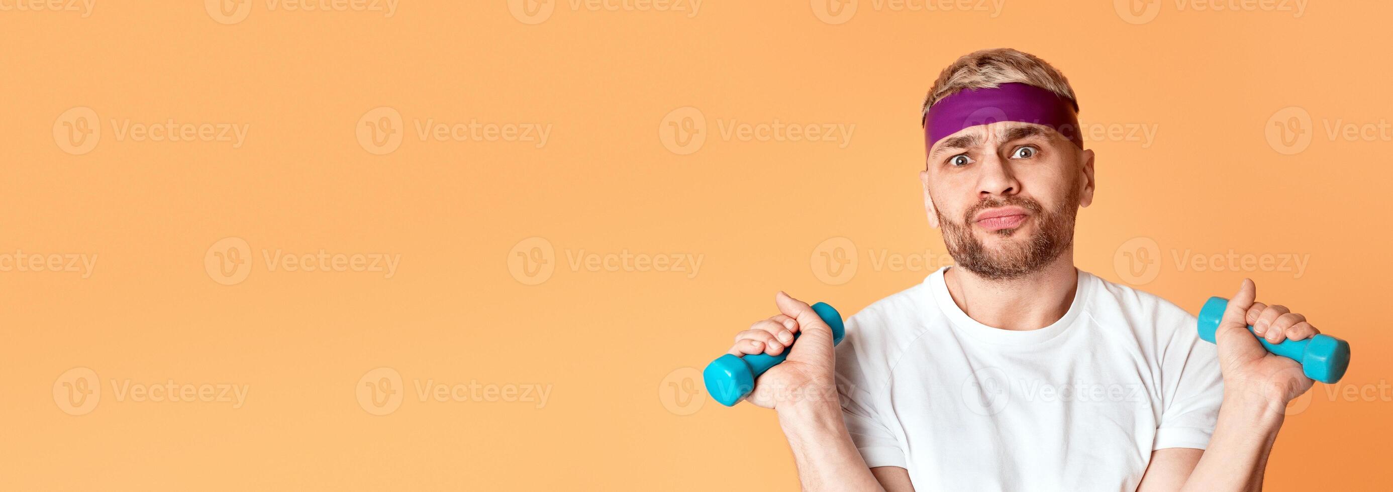 Bored millennial guy doing exercises isolated on yellow background photo