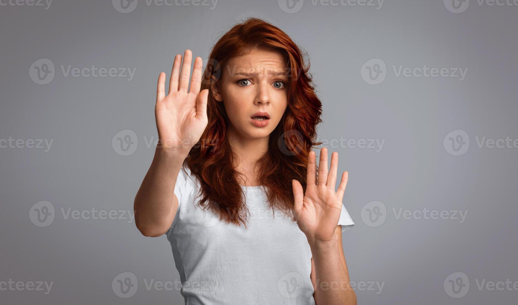No. Scared Red-Haired Girl Gesturing Stop Forbidding Or Warning About Danger Standing On Gray Background. Studio Shot photo