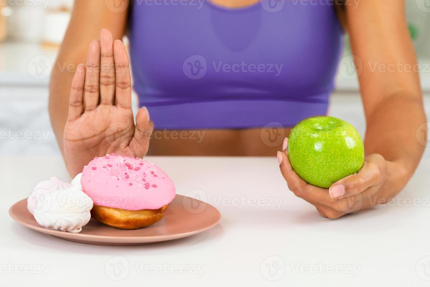 Eat Less Sugar Concept. Close up of black girl giving up eating cake, choosing healthy tasty green apple photo