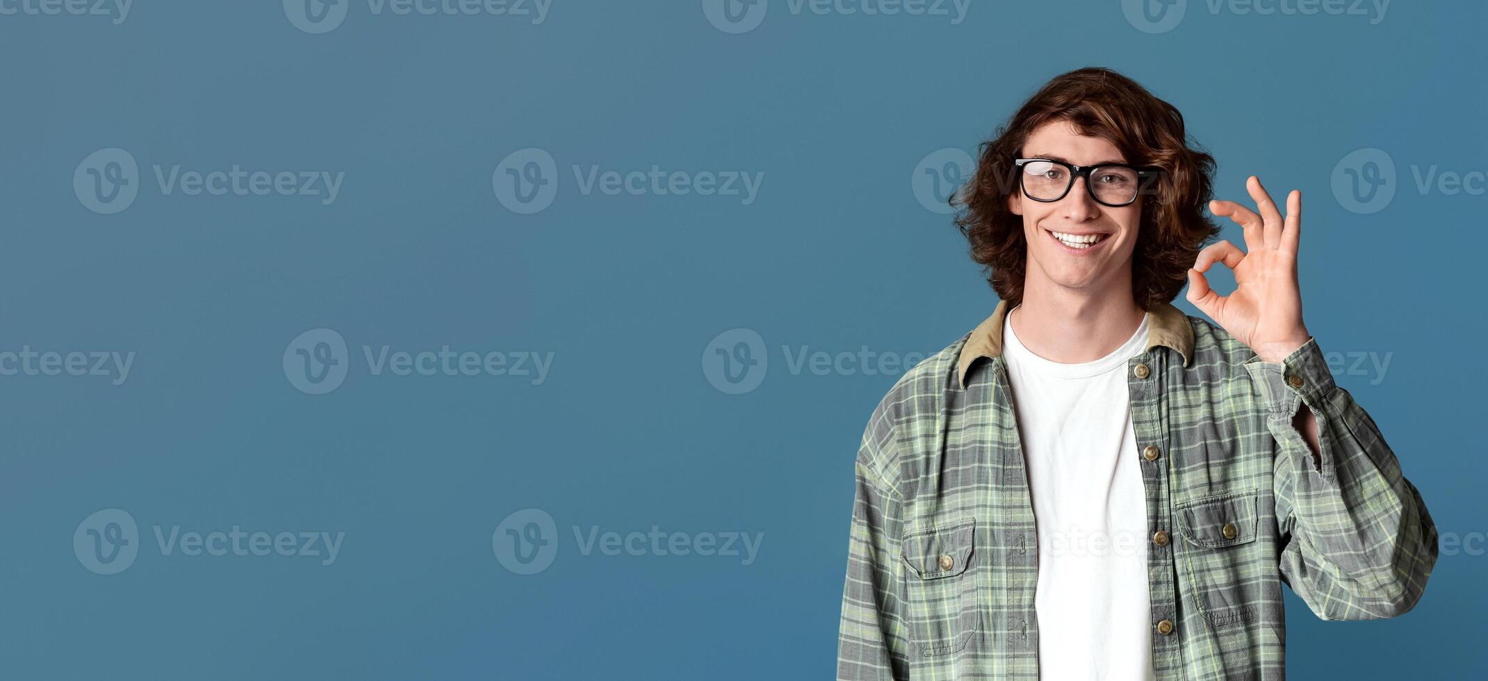 Curly millennial guy showing okay gesture, expressing positivity on turquoise background photo