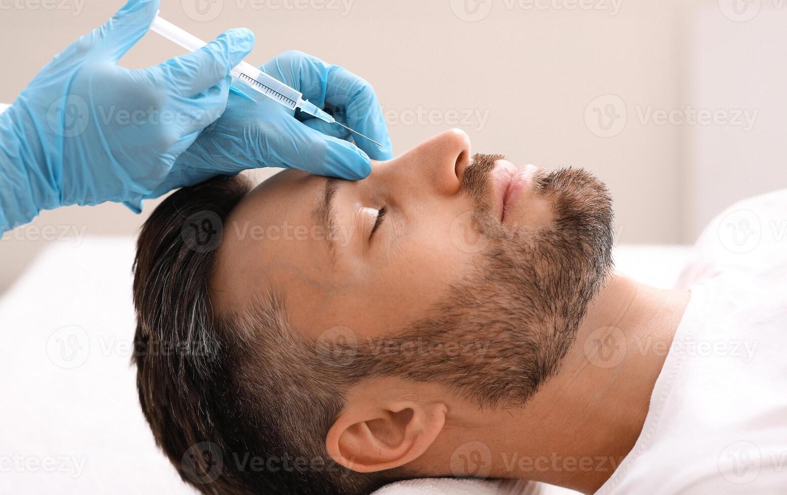 Side view of middle-aged man getting beauty injection in nose at aesthetic clinic. Plastic surgeon injecting anti-aging filler in handsome bearded man nose, having plastic correction, closeup photo