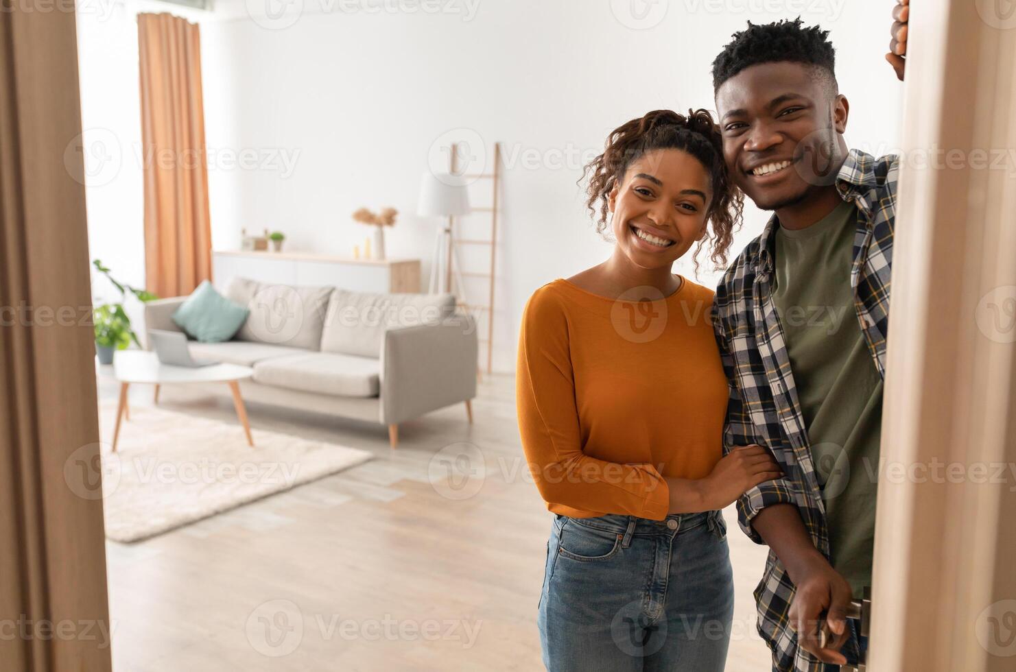 Joyful African American Family Couple Embracing Standing In Opened Doors Of Their New Home, Smiling Looking At Camera. Housing For Married Couple. Real Estate Property Ownership Concept photo