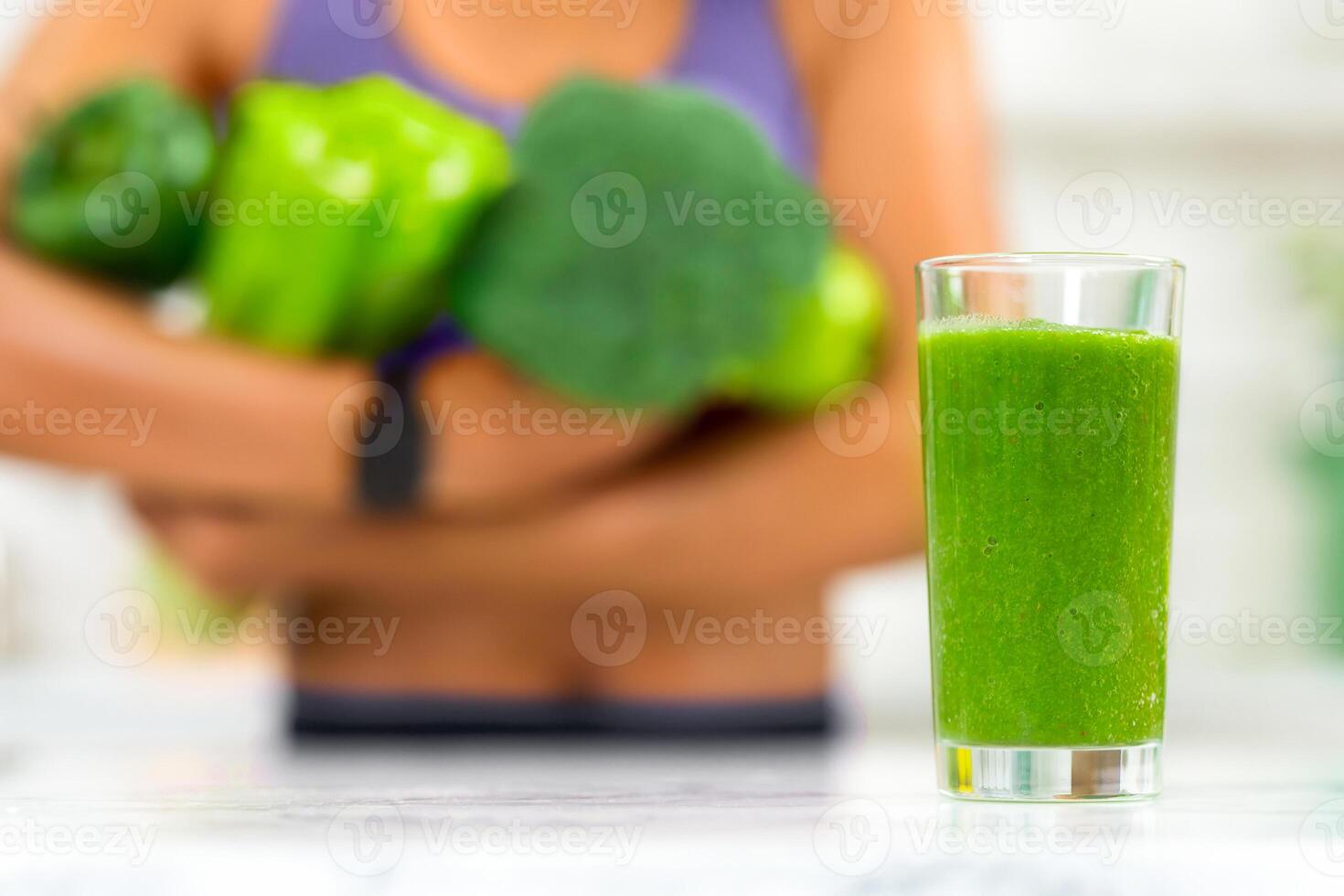 Healthy Smoothie. Unrecognizable african woman holding green vegetables, selective focus on blended green juice photo