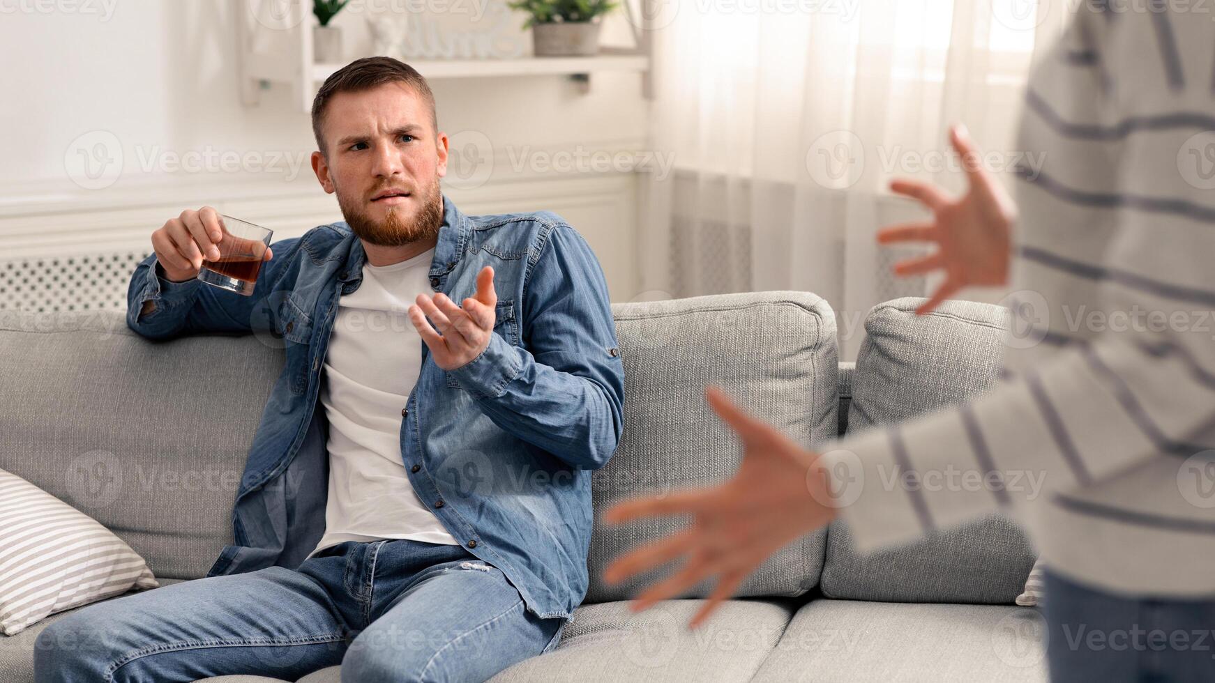 Family issue. Drunk man arguing with his wife, drinking whiskey at daytime photo