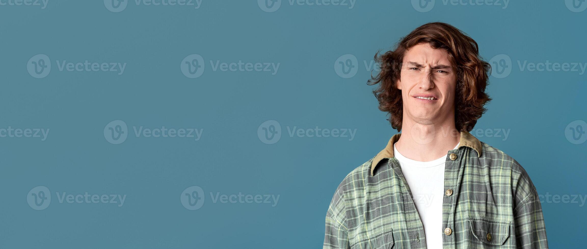Young guy with disgusted expression on turquoise background photo