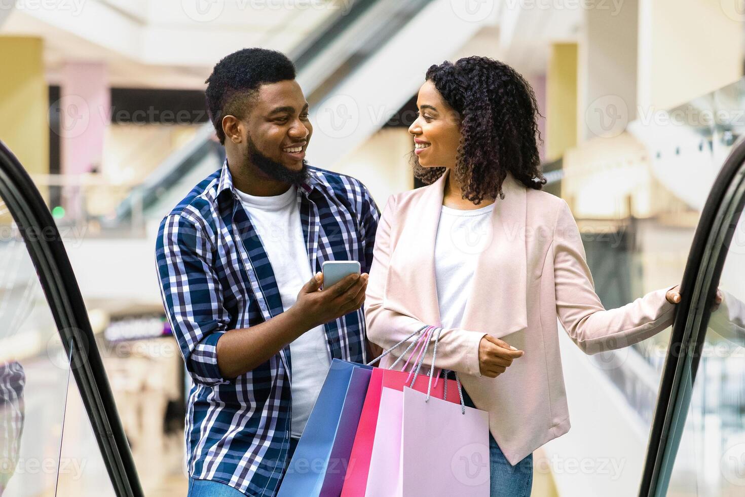 First Meet. Handsome Black Man Introducing With Beautiful Woman In Shopping Center, Asking Her Phone Number While Riding Escalator Together In Department Store, Woman Smiling In Return, Free Space photo