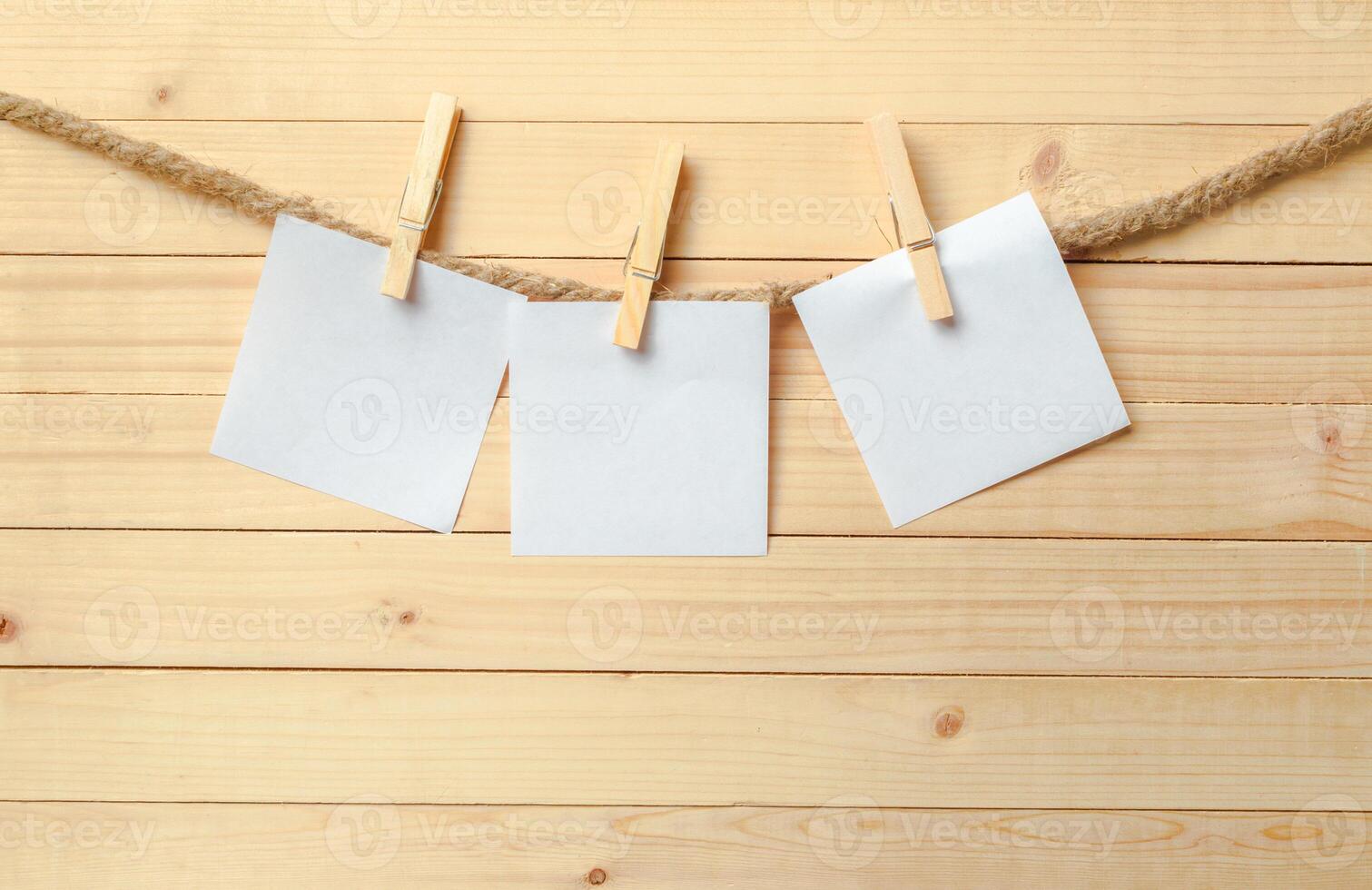 clothespin hanging with blank paper on wooden background photo