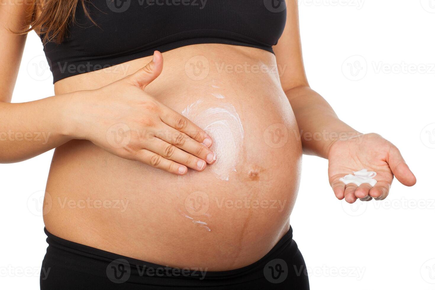 pregnant woman massaging her belly with ointment against stretch marks photo