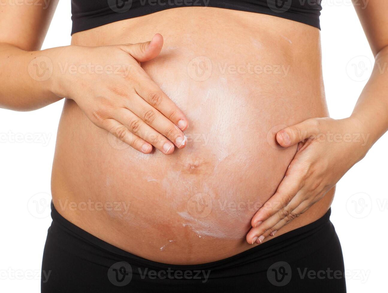 pregnant woman massaging her belly with ointment against stretch marks photo