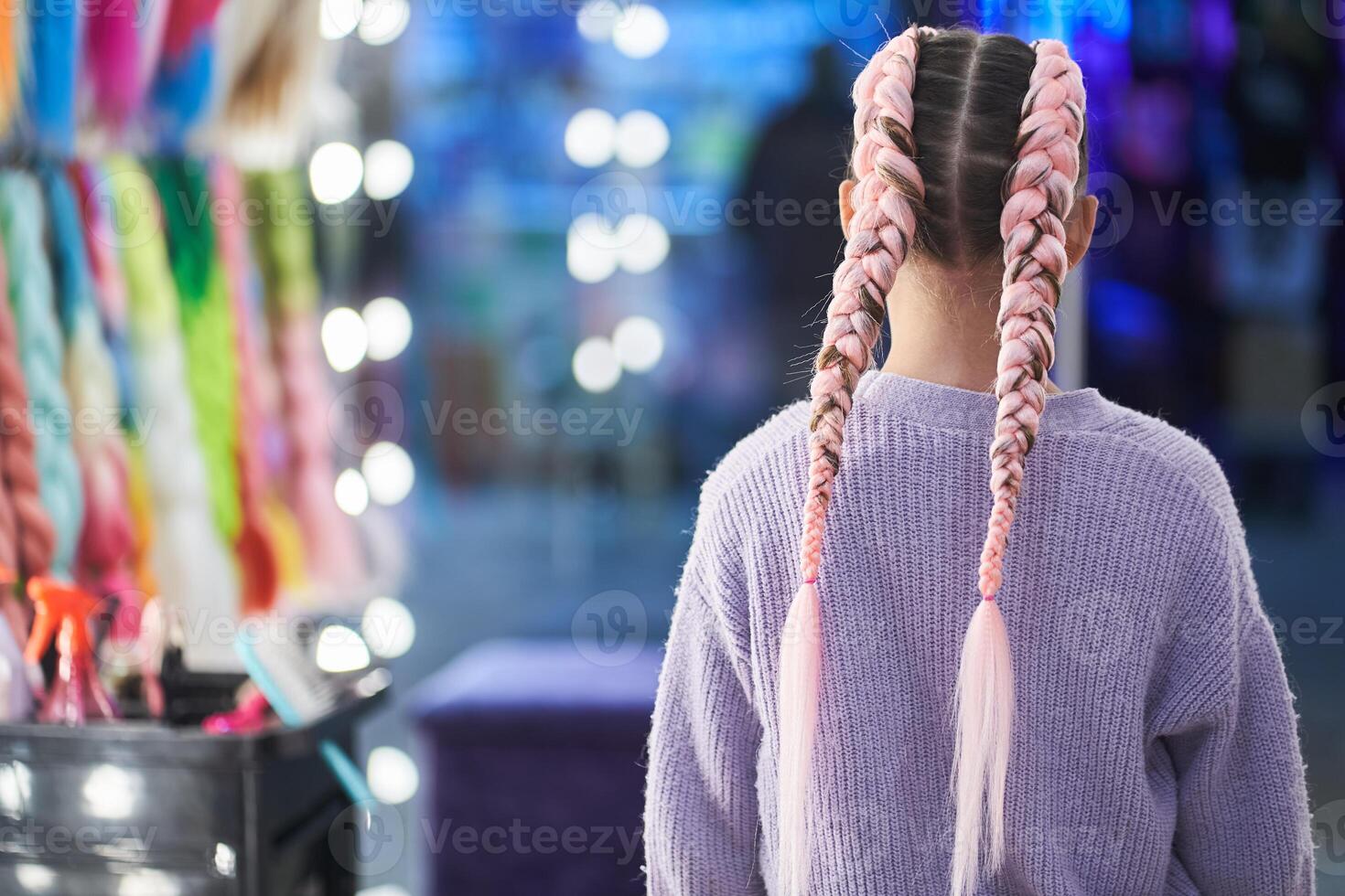 The girl is standing with her back to the camera. An unrecognizable girl with pigtails made of pink kanekalon. With a place to copy photo