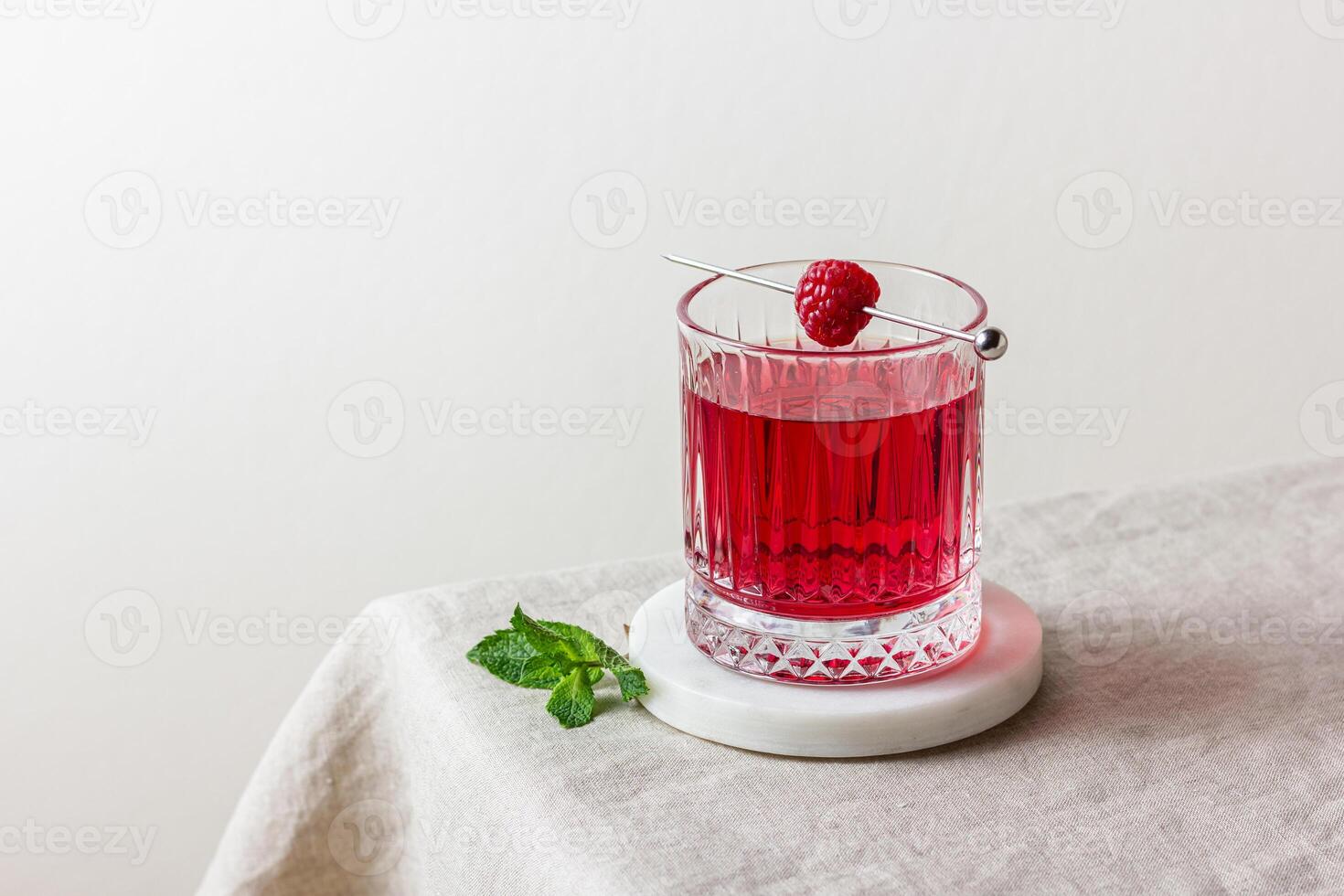 Cocktail with raspberry in a glass on a marble stand photo