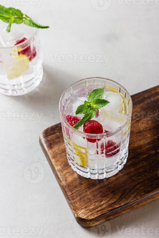 Raspberry cocktails with ice in a glass on a light background photo